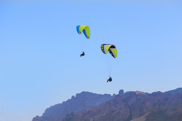 parachutists on paragliders fly over the mountains