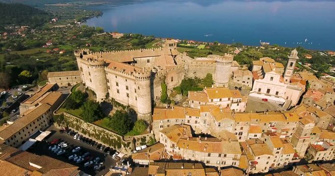 Aerial, tilt up, drone shot of the Castello Orsini-Odescalchi castle and lake Lago di Bracciano , sunny day, in Lazio, Italy
