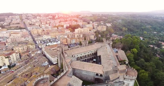 Aerial, tracking, drone shot overlooking the Castello Orsini-Odescalchi castle and Bracciano town, during sunset, in Lazio, Italy
