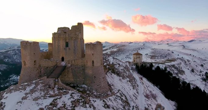 Aerial, drone shot, passing the Castello Rocca Calascio fortress, towards the Santa Maria della Pieta church, winter dusk, in Abruzzo, Italy