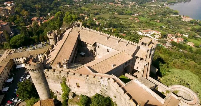 Aerial, rising, drone shot away from the Castello Orsini-Odescalchi castle, sunny day, in Bracciano, Lazio, Italy