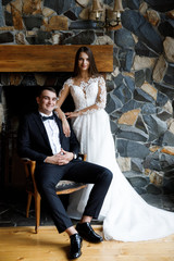 Stylish bride and groom posing in hotel room. Happy luxury wedding couple embracing. Romantic passionate sensual moment. Woman and man together