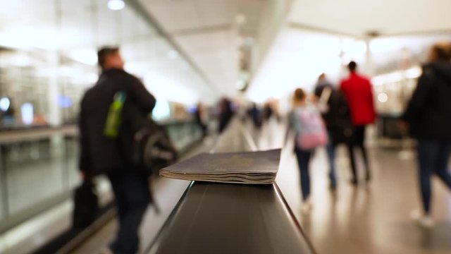 Fixed selective focus close up shot of a Canadian passport on moving walkway or sidewalk handrail in the airport. air port terminal interior concept.