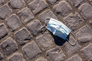 The End Of Coronavirus. Protective mask thrown down on the cobblestone road.