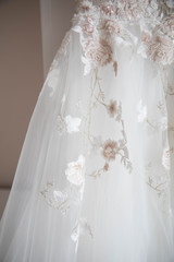 White wedding dress with lace hanging on a hanger.