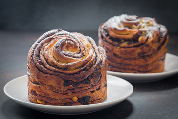 Homemade cruffin cake, made with yeast. Filled with butter, chiocolate, nuts and raisins. Modern food. Dark background.