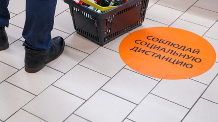 the inscription on the floor of the supermarket: keep a social distance.