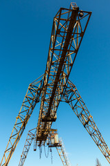 Vintage working gantry crane rusty yellow, bottom view, close-up against a blue spring sky