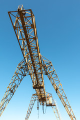 Vintage working gantry crane rusty yellow, bottom view, close-up against a blue spring sky