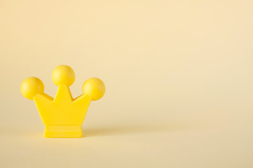 Miniature yellow crown on a beige background. Royal headdress. Power and leader concept.
