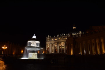 Night view of the illuminated fountains in St. Peter's Square with the basilica in the background with no people. Travel concept.