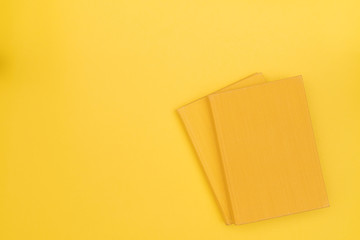 Two yellow books with blank cover on a yellow background. Hard cover. Top view. Copy space