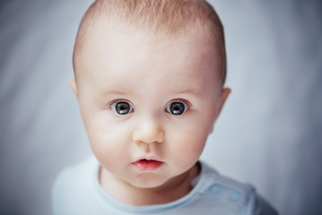 The cutest baby looking at the camera with beautiful deep eyes. 
