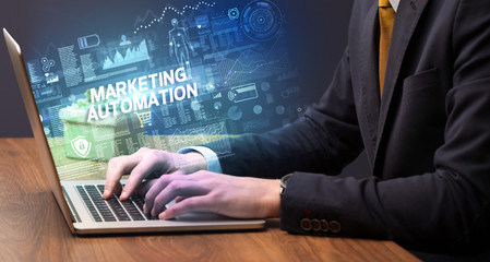 Businessman working on laptop with MARKETING AUTOMATION inscription, cyber technology concept