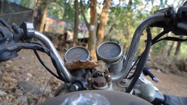 selective focus shot of a motorcycle handlebar dashboard with speedometer gauges. abandoned rusty and dusty Indian cruiser motorbike junk concept.