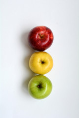 Три разноцветных яблока красное зеленое желтое на белом фоне