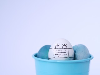 Easter eggs with a self protection face mask, colored with a natural red cabbage, during a coronavirus outbreak in easter celebration time.