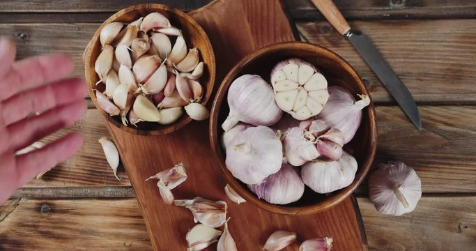 Man's hand puts cloves of garlic on a plate.
