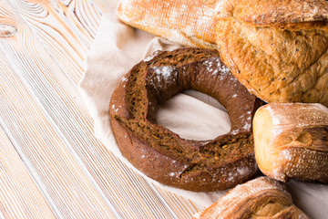 Group of different breads on a light wooden background.