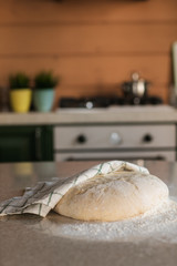 Yeast dough in flour lies on a stone table in the kitchen