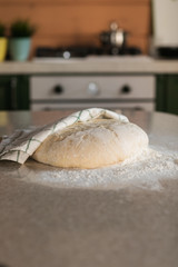 Yeast dough in flour lies on a stone table in the kitchen