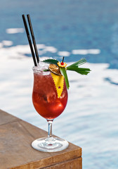 Refreshing cocktail with ice cubes perfect for outdoor event. Fancy beverage decoration with crafted leaf, lemon sliced and orange zest. Pool side area in hotel.