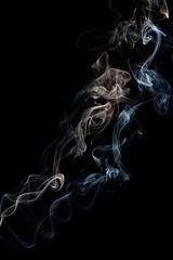 Two delicate columns of smoke from incense stick isolated on black background, selective focus