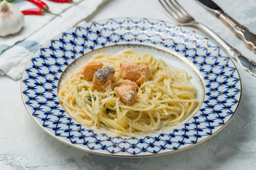 Spaghetti pasta with salmon on grey concrete table