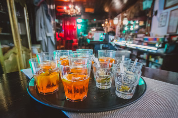Appetizer drinks and shots waiting on a serving board in a bar waiting for first guests at a pary. Party atmosphere and some drinks in the foreground