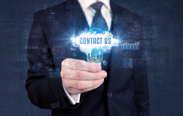 Businessman holding a light bulb with CONTACT US inscription, new business concept