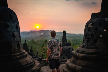 man watching sunset at borobudur indonesia - obrazy, fototapety, plakaty