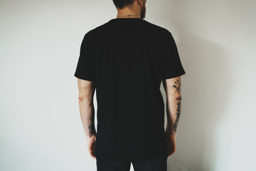 Young hipster wearing black jeans and blank black t-shirt with empty space for  logo, text or...