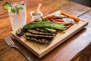 Grilled vegetables, asparagus mushrooms, onions, zucchini and carrots on a wooden cutting board, whit lemonade drink