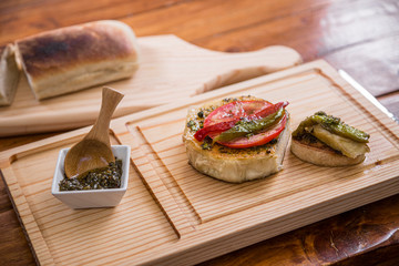 grilled provolone with tomato basil and olive oil accompanied whit chimichurri sauce on wooden cutting board