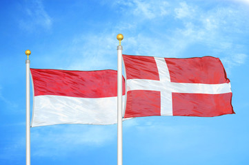 Indonesia and Denmark two flags on flagpoles and blue cloudy sky