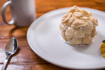 Dessert, ball of sweet flakes whit cream and peach, on a round white plate and cup of coffee 