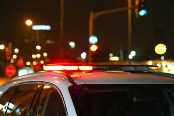 Closeup of red lights on top of a police vehicle at night. Selective focus, blur.