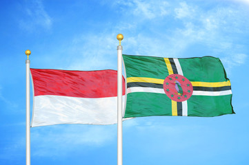 Indonesia and Dominica two flags on flagpoles and blue cloudy sky