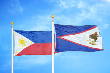 Philippines and American Samoa two flags on flagpoles and blue cloudy sky