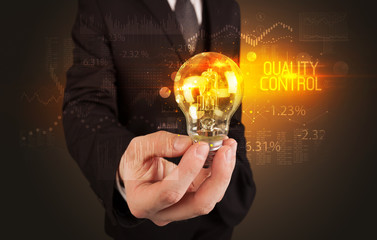 Businessman holding lightbulb with QUALITY CONTROL inscription, Business technology concept