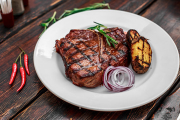 A large steak with spices and vegetables on the grill