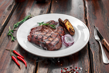 A large steak with spices and vegetables on the grill