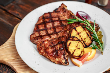 A large steak with spices and vegetables on the grill