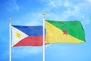 Philippines and French Guiana two flags on flagpoles and blue cloudy sky