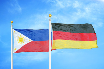 Philippines and Germany two flags on flagpoles and blue cloudy sky
