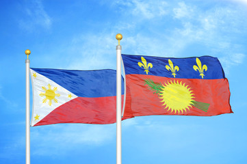 Philippines and Guadeloupe two flags on flagpoles and blue cloudy sky