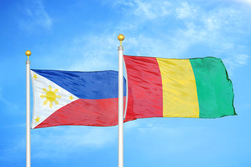 Philippines and Guinea two flags on flagpoles and blue cloudy sky