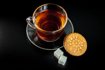 cup of tea with sugar and cookies on a dark background