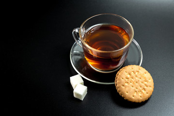 cup of tea with sugar and cookies on a dark background