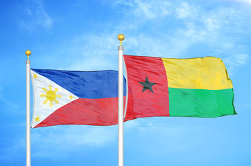 Philippines and Guinea-Bissau two flags on flagpoles and blue cloudy sky